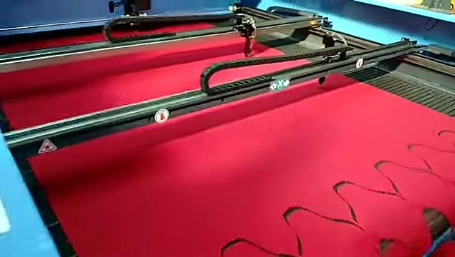 Dual black gantries over red fabric nested cuts (SKU ask)