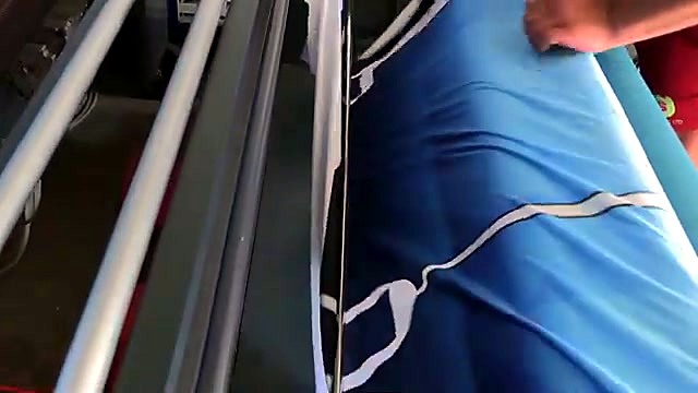 Operator smoothing sublimated fabric into feed (SKU ask)