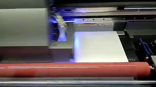 F-UVDTF/600 carriage with UV glow over white UV-DTF film above the red laminator roller