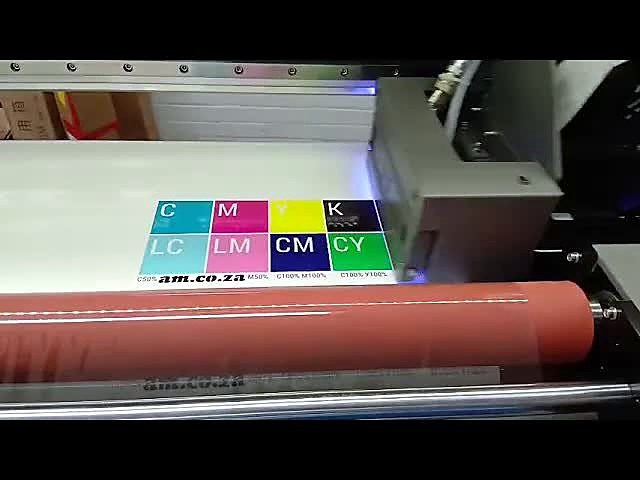 F-UVDTF/600 printing a CMYK colour block on UV-DTF film above the red laminator roller
