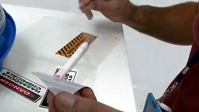 Hands peel hazard-stripe sticker from carrier (SKU ask)