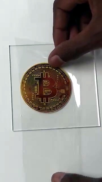 Hands apply gold Bitcoin sticker to acrylic (SKU ask)