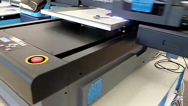 Red e-stop + UV cure glow over macaw on FlatPRINT deck (SKU ask)