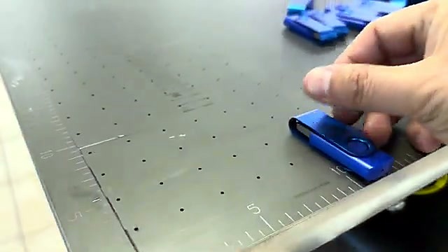 Hand placing blue USB on FlatPRINT grid bed (SKU ask)