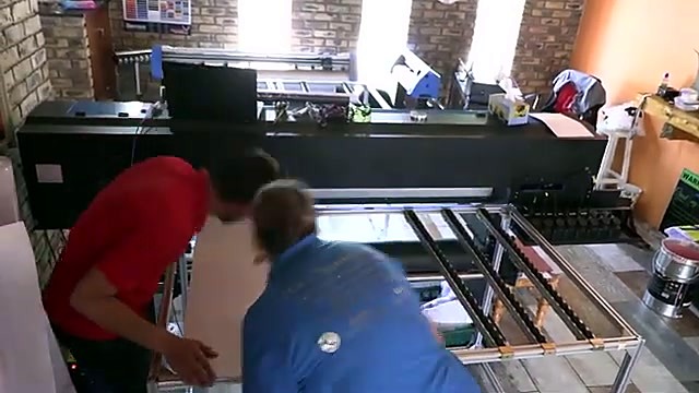 Two operators load rigid board on hybrid bed (SKU ask)