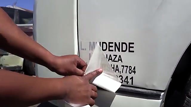 Applying vinyl lettering to white taxi (SKU ask)
